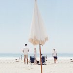 مظلة الشاطئ البيضاء مع عمود خشبي